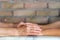 Nurse holding hands of elderly woman against blurred brick wall background.