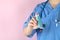Nurse holds asthma inhaler on pink background