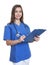 Nurse with long dark hair and clipboard writing note