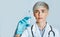 Nurse makes injection. Woman in white coat with medical gloves looks at syringe