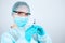 Nurse in a medical gown, mask and protective gloves with transparent glasses on her face with a syringe in her hands