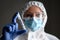 Nurse in medical PPE suit holds tube of coronavirus PCR test
