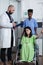 Nurse moving patient sitting in wheelchair holding iv pole to treatment room while doctor gives consult