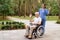 A nurse and an old man who is sitting in a wheelchair happily greet someone