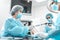 Nurse in protective mask giving laparoscopic instrument to surgeon