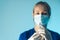 nurse with a protective mask holiding a vaccination syringe - light blue background closeup