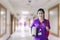 Nurse in purple uniform with backpack standing and holding book