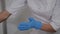 A nurse in rubber gloves spray a disinfectant on her hands, close-up. A nurse squirting on hand disinfectant solution.