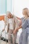 nurse and senior patient with walker smiling each other in hospital