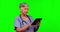 Nurse, senior woman and tablet on green screen in studio isolated on a background mockup. Medical professional