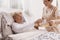Nurse serves tea to an elderly lady in a private nursing home