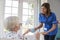 Nurse serving tea to senior woman at home, close up