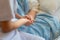 Nurse sitting on a hospital bed next to an older woman helping hands, care for the elderly concept