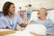 Nurse Sitting By Male Patient\'s Bed In Hospital