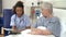 Nurse Sitting By Senior Female Patient\'s Bed In Hospital