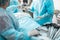 Nurse standing near table with laparoscopic tools and assisting the surgeon