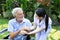 A nurse take care a senior male on wheelchair in his garden at home