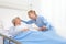 Nurse take comfort elderly woman lying in the hospital room bed, by stroking her and holding the arm where the drip needle is,