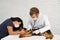 Nurse and vet examining heartbeat of german shepherd puppy on white table.