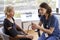 Nurse Wearing Scrubs In Office Checking Senior Female Patients Blood Pressure