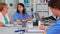 Nurse writing on clipboard while profesional teamworkers having medical meeting