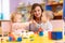 Nursery teacher looking after children in nursery. Little toddlers girl and boy play together with toys.