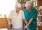 Nursing assistant helping senior woman with walking frame