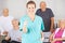 Nursing assistant holding thumbs up in front of senior people