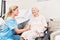 Nursing lady looks after senior woman in wheelchair