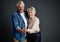 Nurturing their love. Studio shot of an affectionate senior couple holding a budding plant against a grey background.