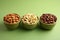 Nut trio in ceramic bowl on green backdrop, promoting healthy eating