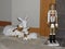 A nutcracker and white porcelain deer as holiday decorations.