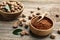 Nutmeg powder and seeds with green leaves on wooden table