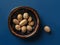 Nutmeg seeds whole and halved on a black plate over blue background. Muscat nuts for spice and seasoning concept. Myristica