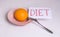 Nutrition concept Transition to proper nutrition Word diet on a white background with an orange in a plate