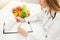 Nutritionist doctor writing diet plan on table