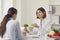 Nutritionist holding broccoli and telling young woman about benefits of healthy eating