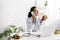 Nutritionist talking on smartphone near laptop and apple