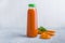 Nutritious detox carrot juice in glass bottle. Alkaline diet concept. Organic vegetarian drink and fresh carrots on gray