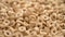 Nutritious dry oat cereal rings falling in slow motion close up with rotation.