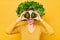 Nutritious food choices. Amazed excited woman with lettuce hair style with green vegetables on her head isolated over yellow