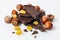 Nuts, sweet raisins and and stack of a dark chocolate on a white background. Ripe wild hazelnuts and bitter chocolate. Natural