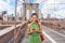 NYC travel phone texting girl holding smartphone on Brooklyn bridge in New York City, Manhattan USA. Asian woman phone