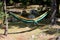 Nylon parachute bag hammock spread between two trees in local park used for resting in shade of large trees