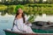 The nymph with long dark hair in a white vintage dress sitting in a boat in the middle of the river.