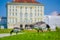 Nymphenburg, Germany - July 30, 2015: Grey birds on green grass standing with palace building facade sligthly burry background, be