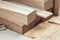 Oak wooden bar blocks materials stacked at carpentry woodwork workshop with tools and sawdust on background. Timber wood blanks at