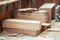 Oak wooden bar blocks materials stacked at carpentry woodwork workshop with tools and sawdust on background. Timber wood blanks at