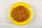 Oat cookie with sunflower seeds in yellow saucer on table. Top view