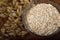 Oat ears stems and oat flakes in a bowl on a dark brown wood background. Top view. oat flakes small size grind. Close up. Useful f